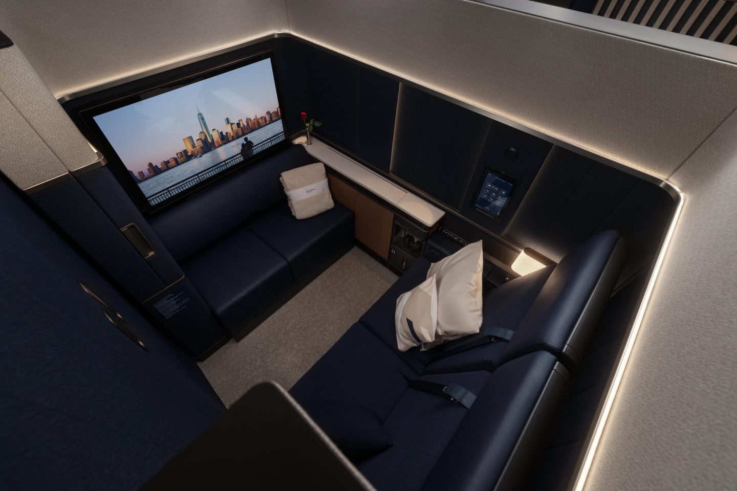 Luxurious private airline suite with large screen, spacious seating and ambient lighting.