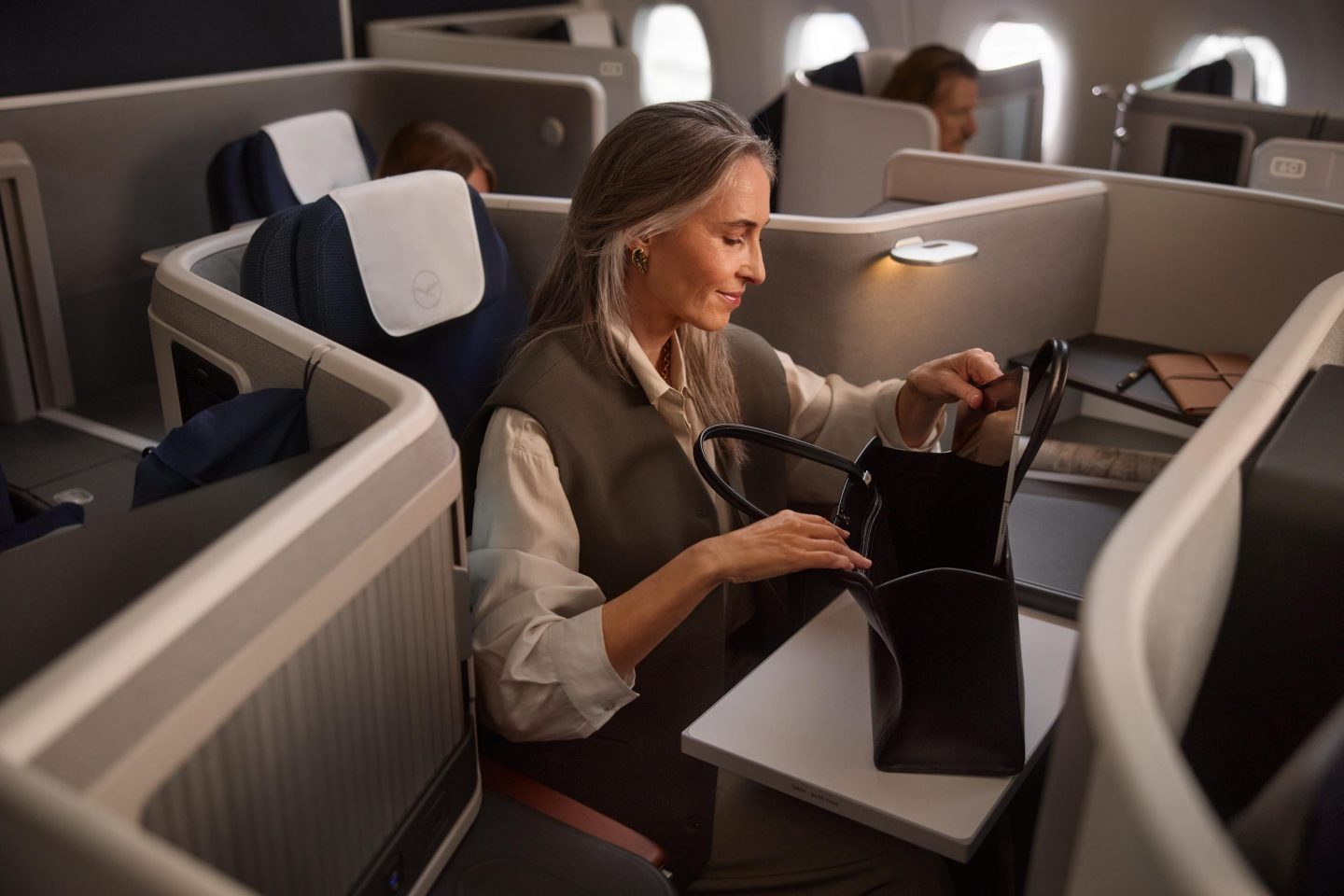 Eine Frau packt ihr elektorisches Ger&auml;t in ihre Tasche in der Business Class auf dem extra space seat // A woman puts her electronic device in her bag in the business class on the extra space seat