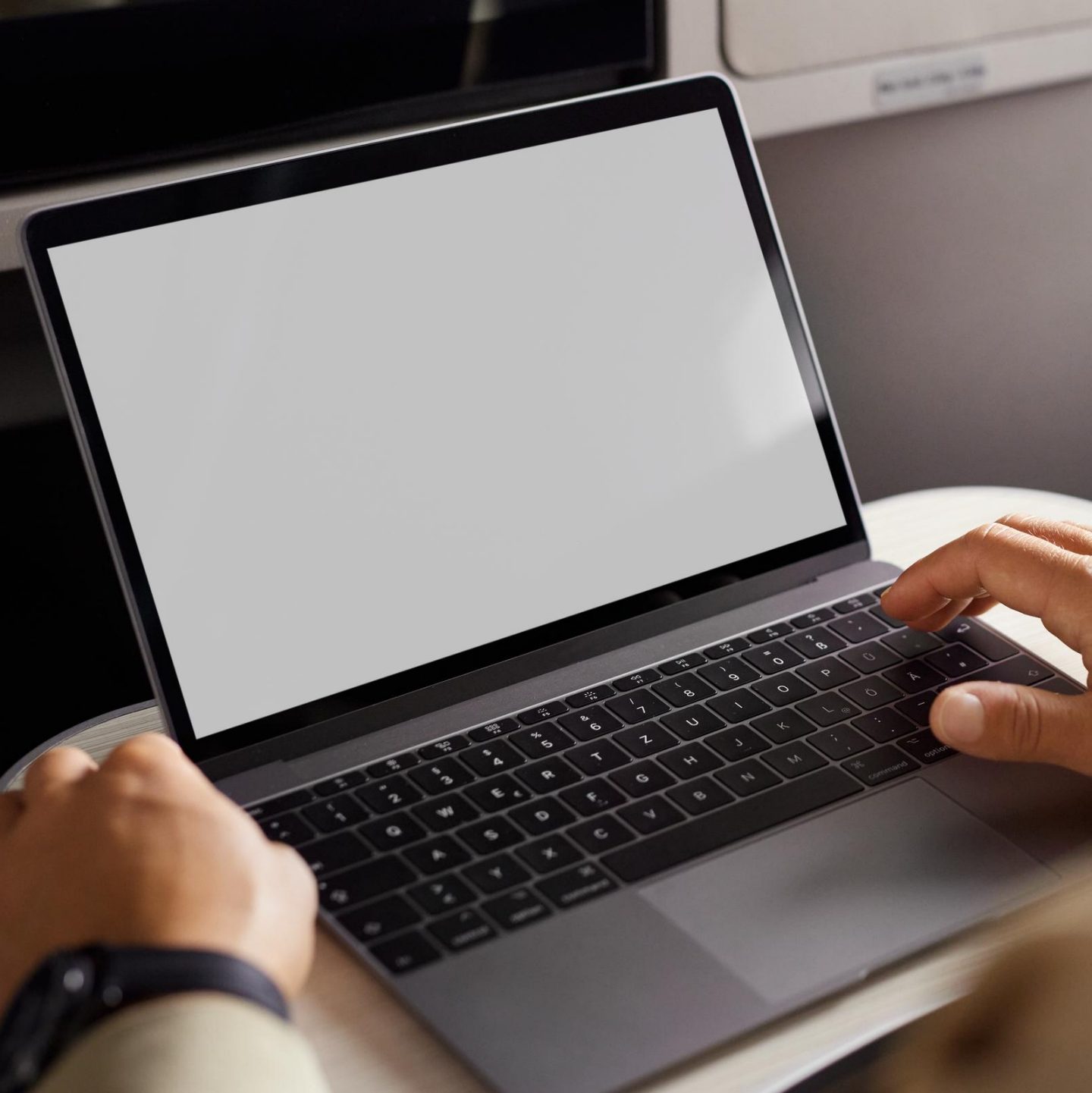 Ein Mann arbeitet in der Business Class an seinem Laptop. // A man works on his laptop in business class.
