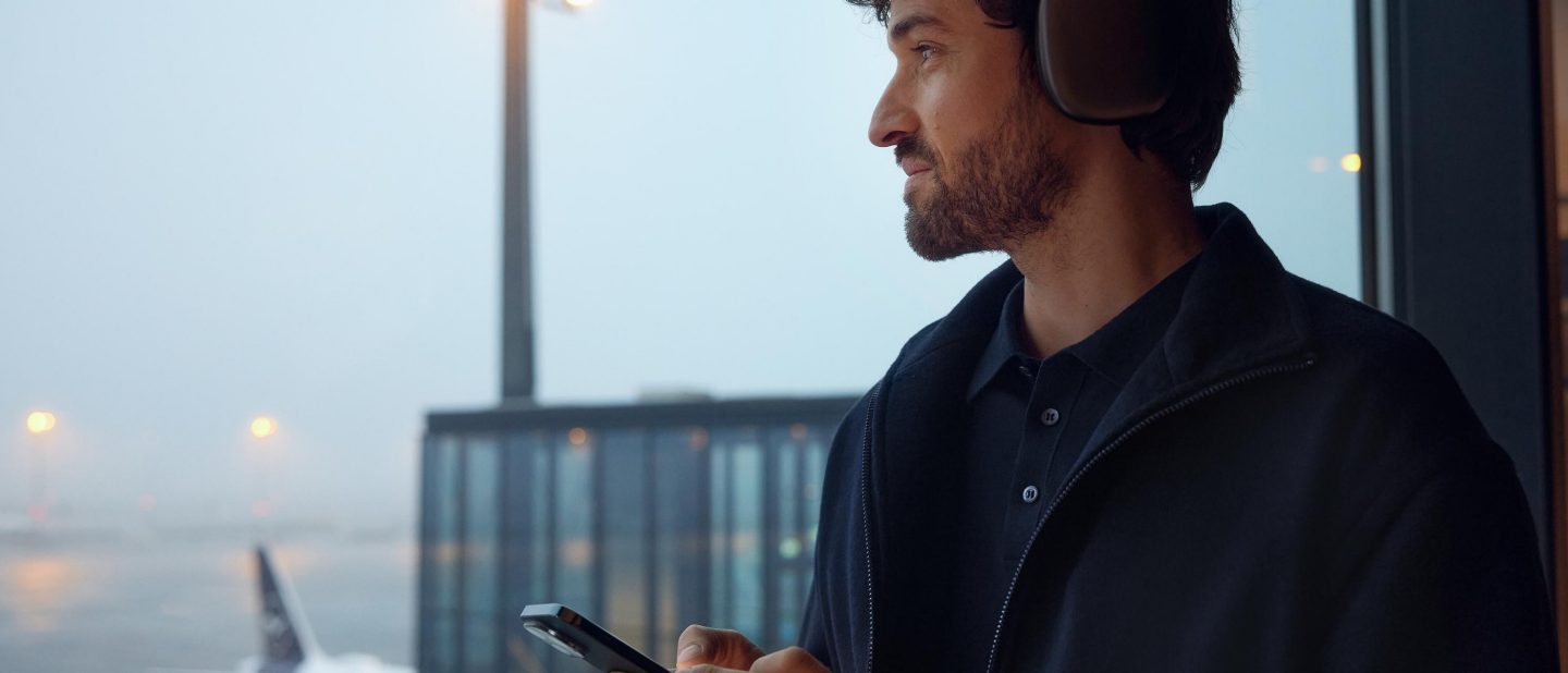 Junger Mann mit Smartphone in der Hand. Er meldet sich mit seiner Travel ID/E-Mail Adresse in seinem Konto an.