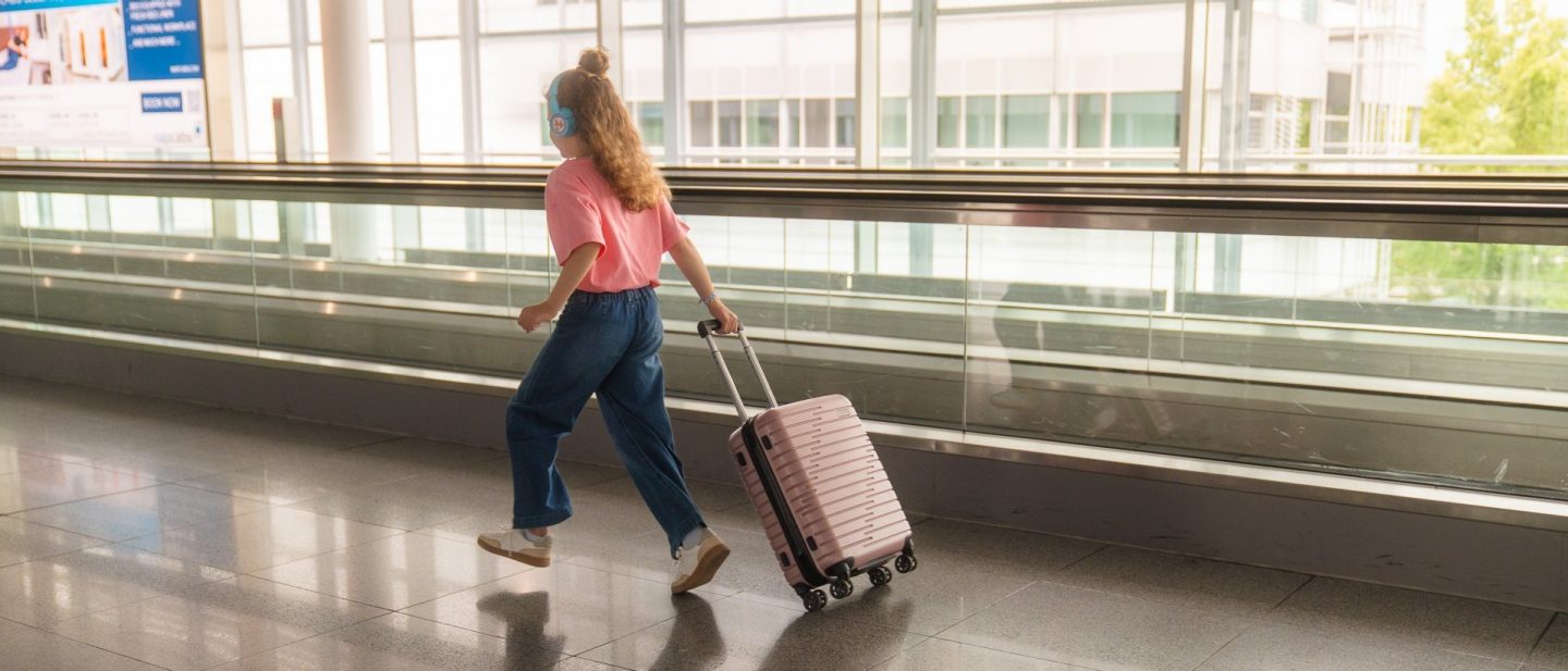 Ein Kind l&auml;uft mit seinem Koffer durch den Flughafen // A child is walking through the airport with their suitcase