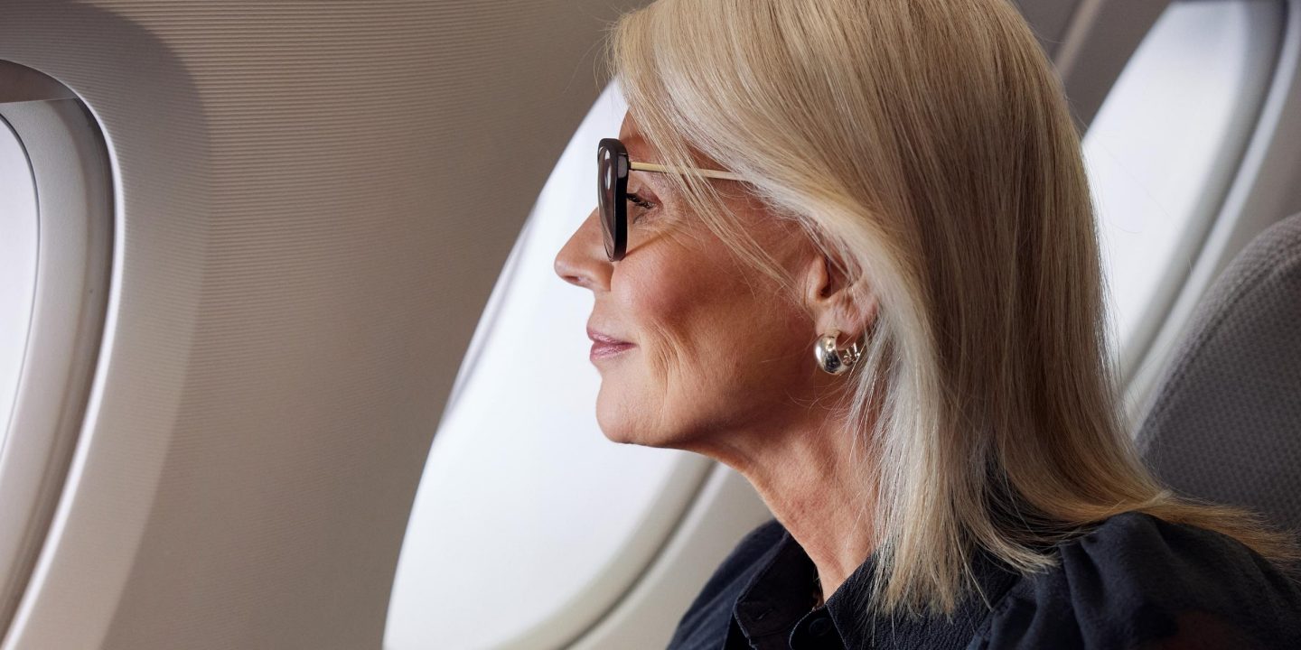 A lady with glasses sitting on a plane.