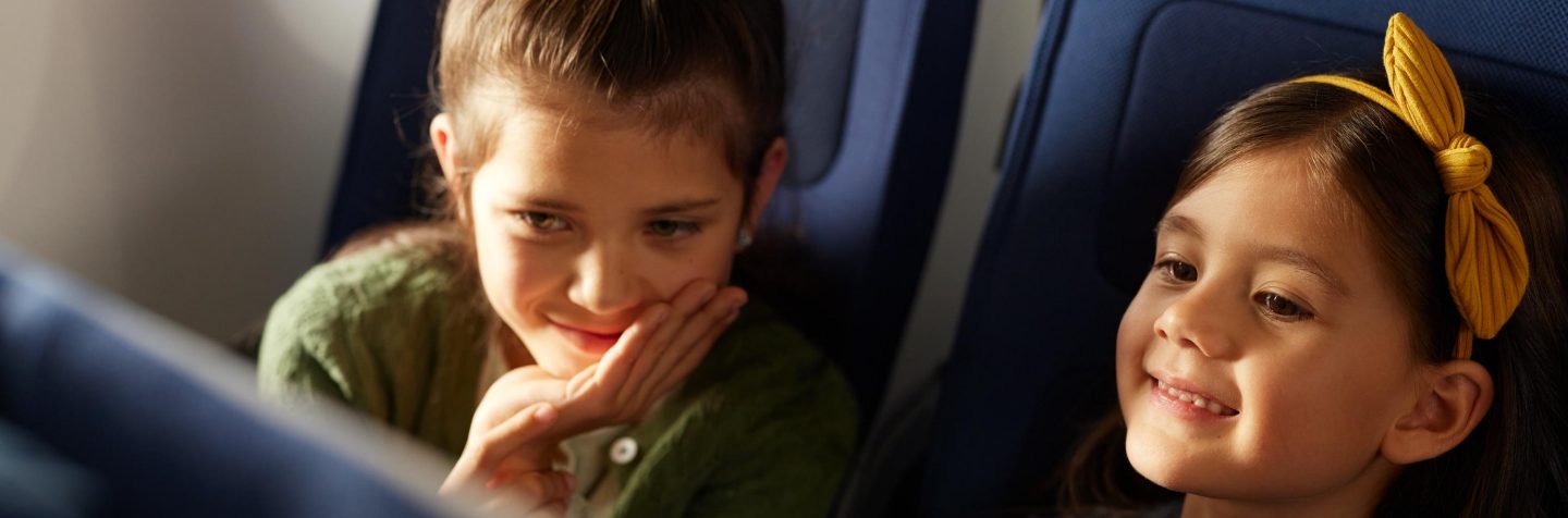Zwei Kinder benutzen das Inflight Entertainment System und l&radic;&sect;cheln. // Thwo children are using the Inflight Entertainment system and smile. 