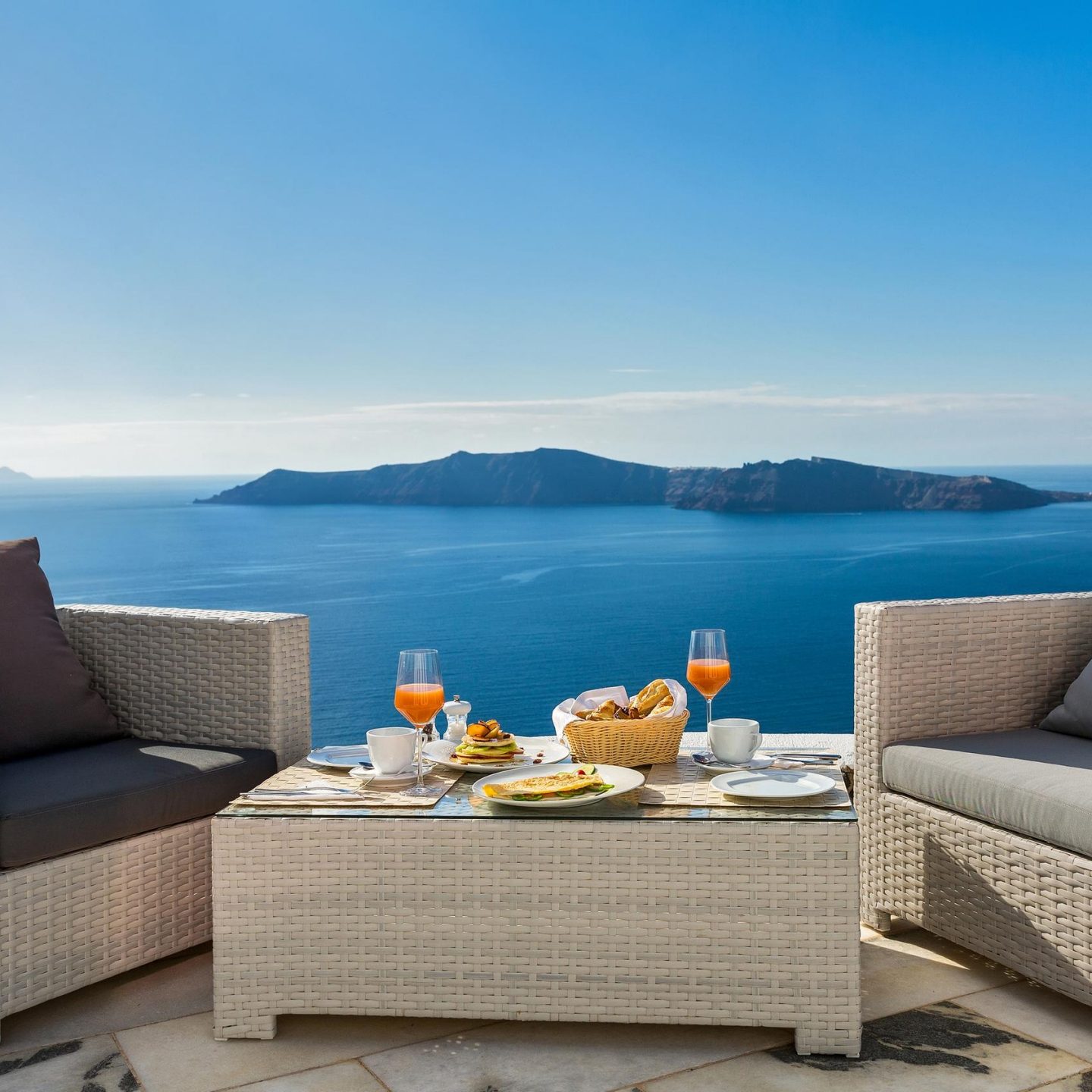 Breakfast table on a patio overlooking the sea.