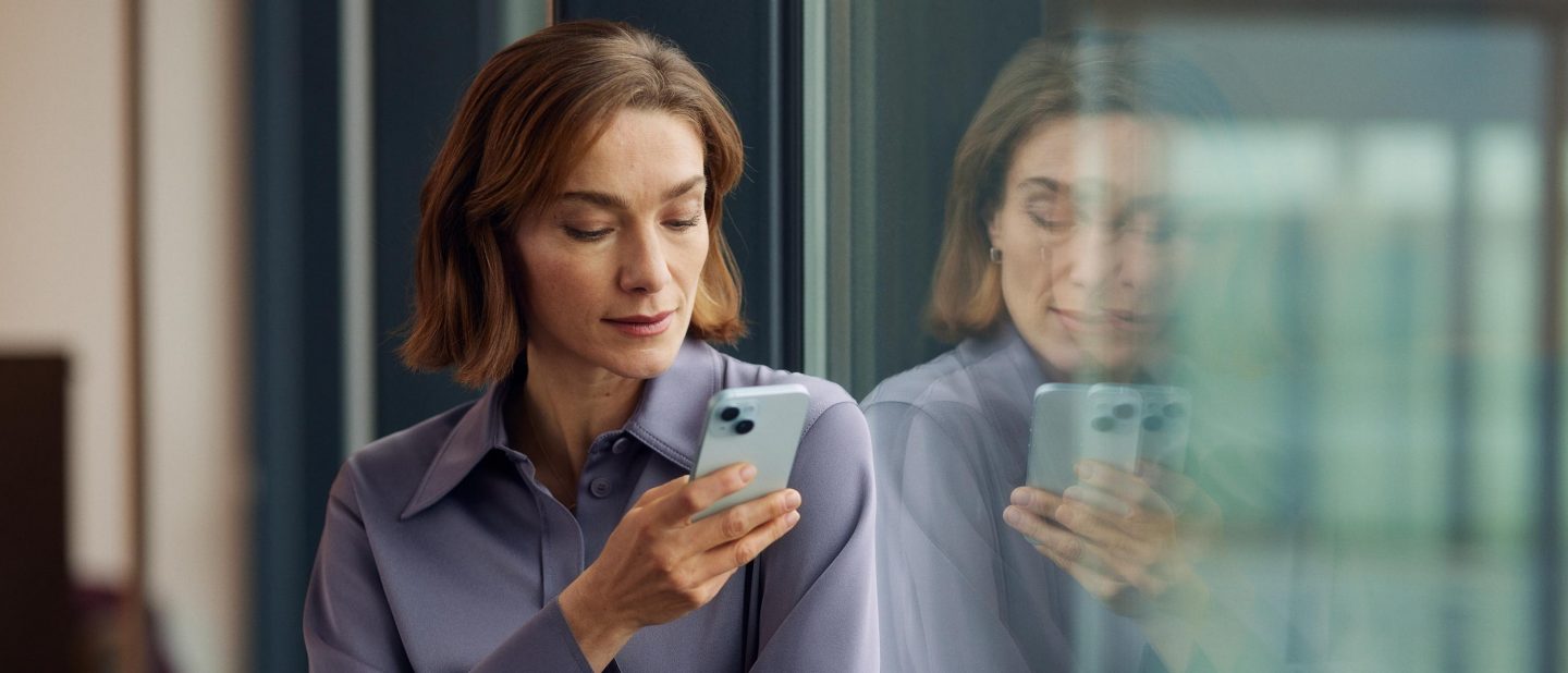 Eine Frau steht in der Lounge am Fenster und telefoniert. // A woman is standing by the window in the lounge talking on the phone.