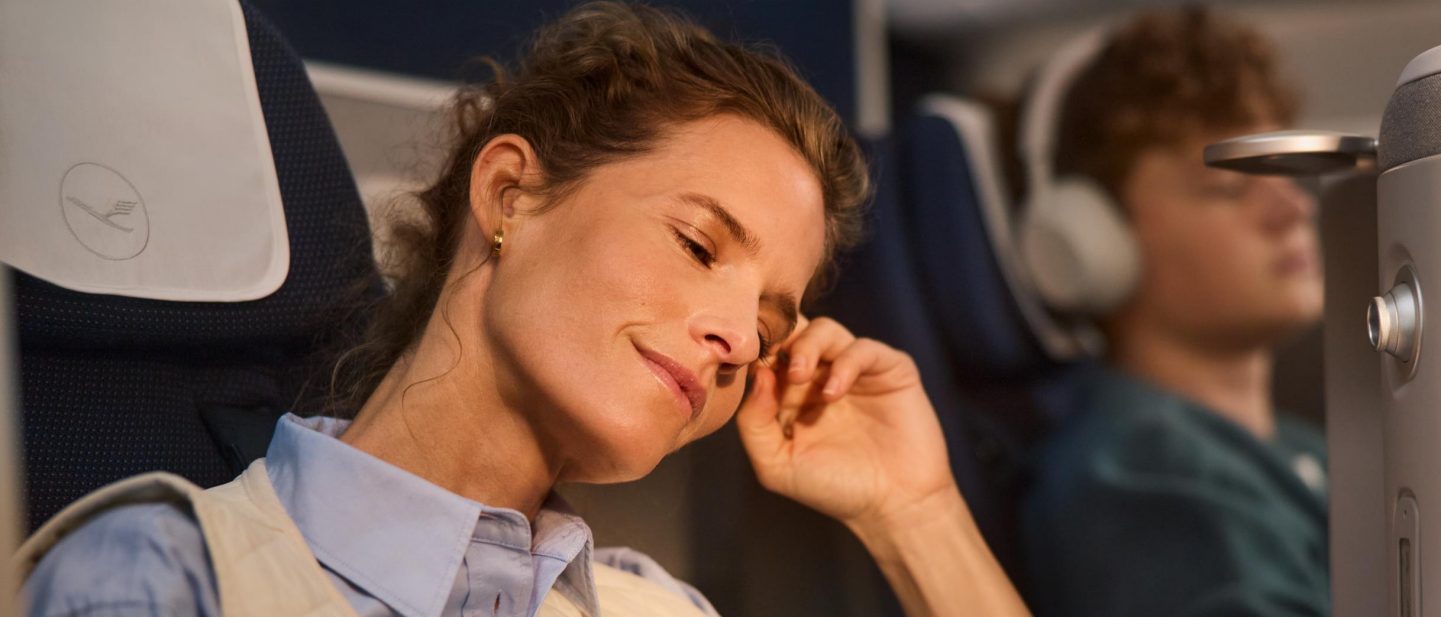 Eine Frau sitzt in der Business Class mit einem Kindle in der Hand // A woman sits in business class with a Kindle in her hand