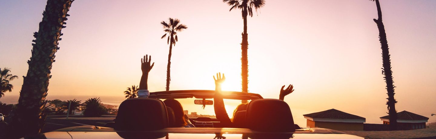 USA, Los Angeles: P&radic;&sect;rchen beim Sonnenuntergang unterwegs im Cabrio. // USA, Los Angeles: Couple on the road in a convertible at sunset.