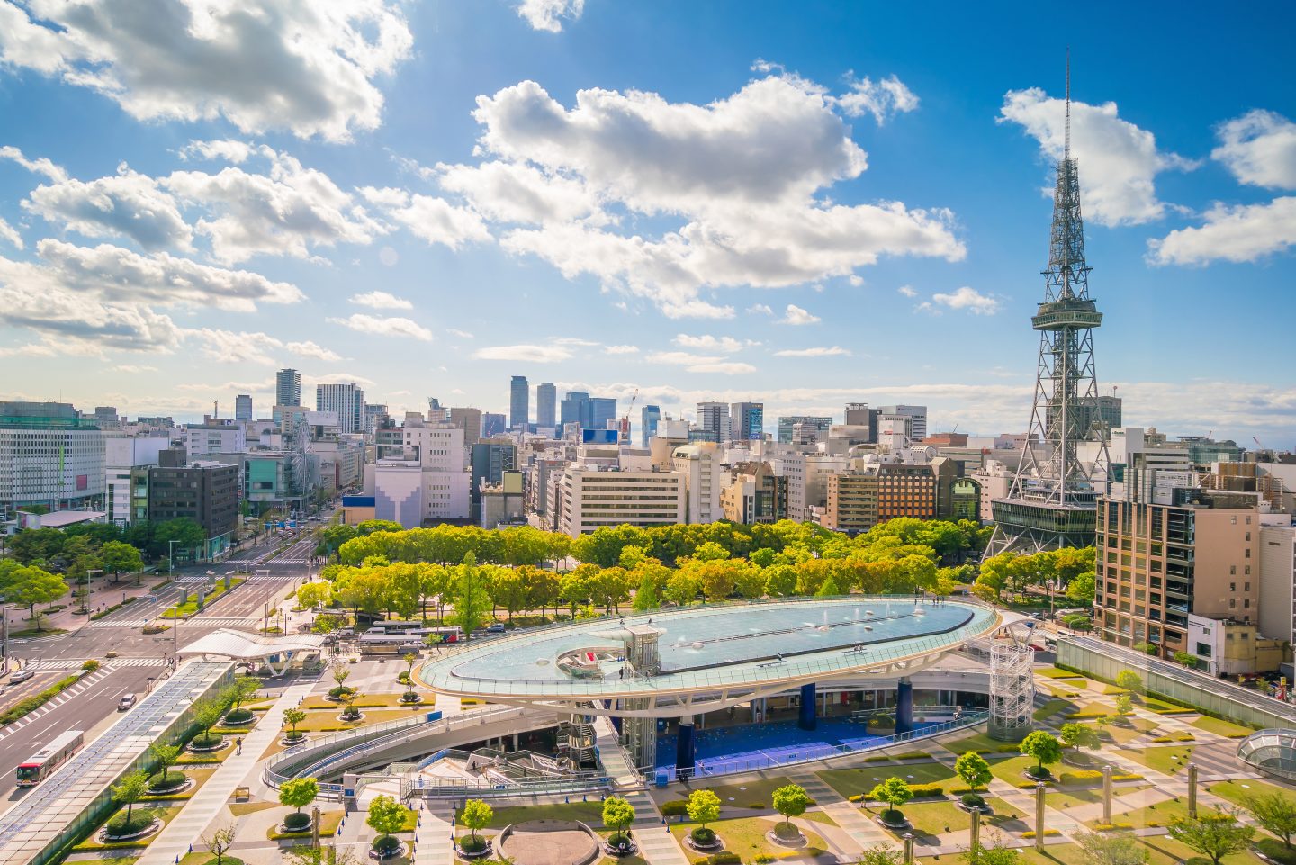 Sunny aerial view of Nagoya's modern skyline, park, and TV tower.