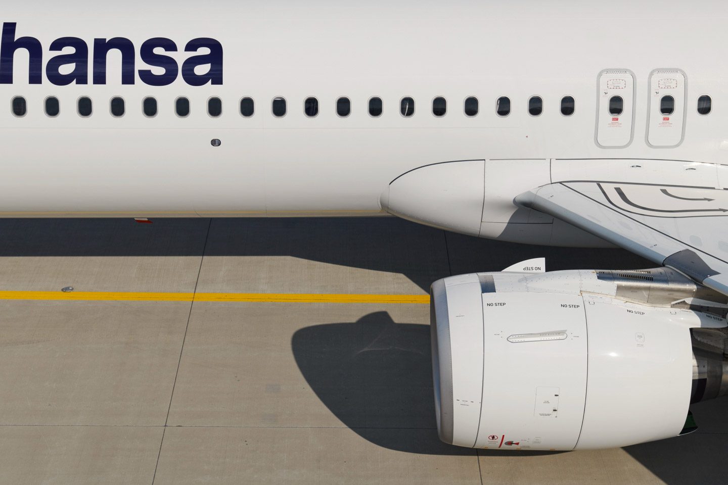 Side view of a Lufthansa aircraft on the apron; windows, wing, and engine are visible.