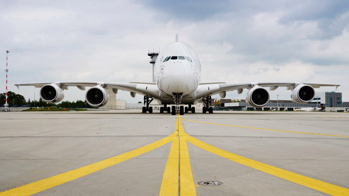 Airbus A380 blanc stationné sur le tarmac, vu de face.