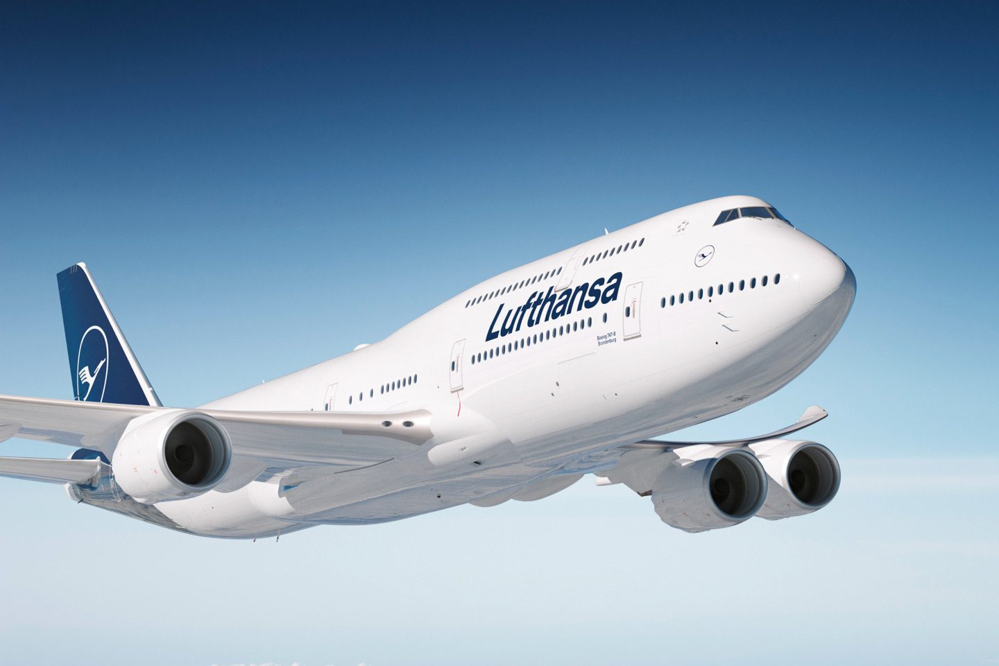 White Lufthansa 747-8 soaring in a clear blue sky.