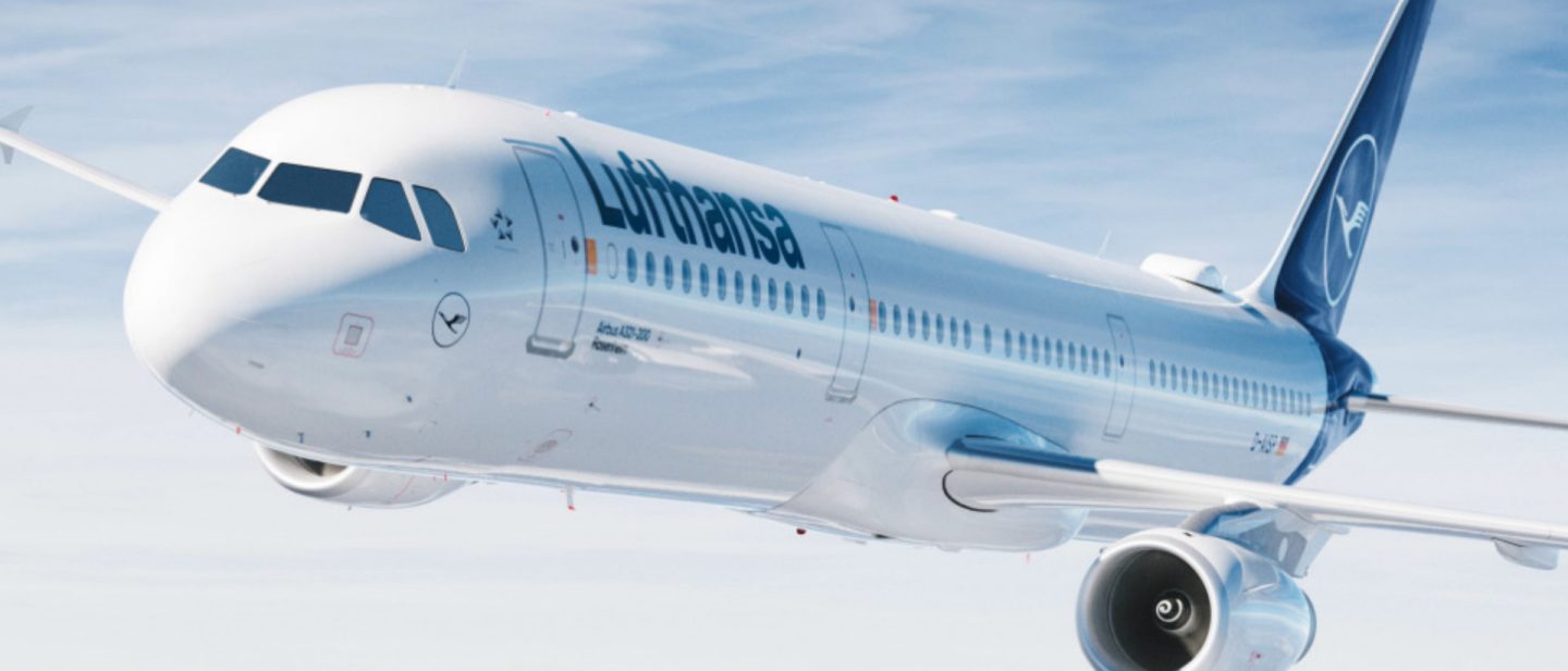 Lufthansa Airbus A321-200 flying against a blue sky.
