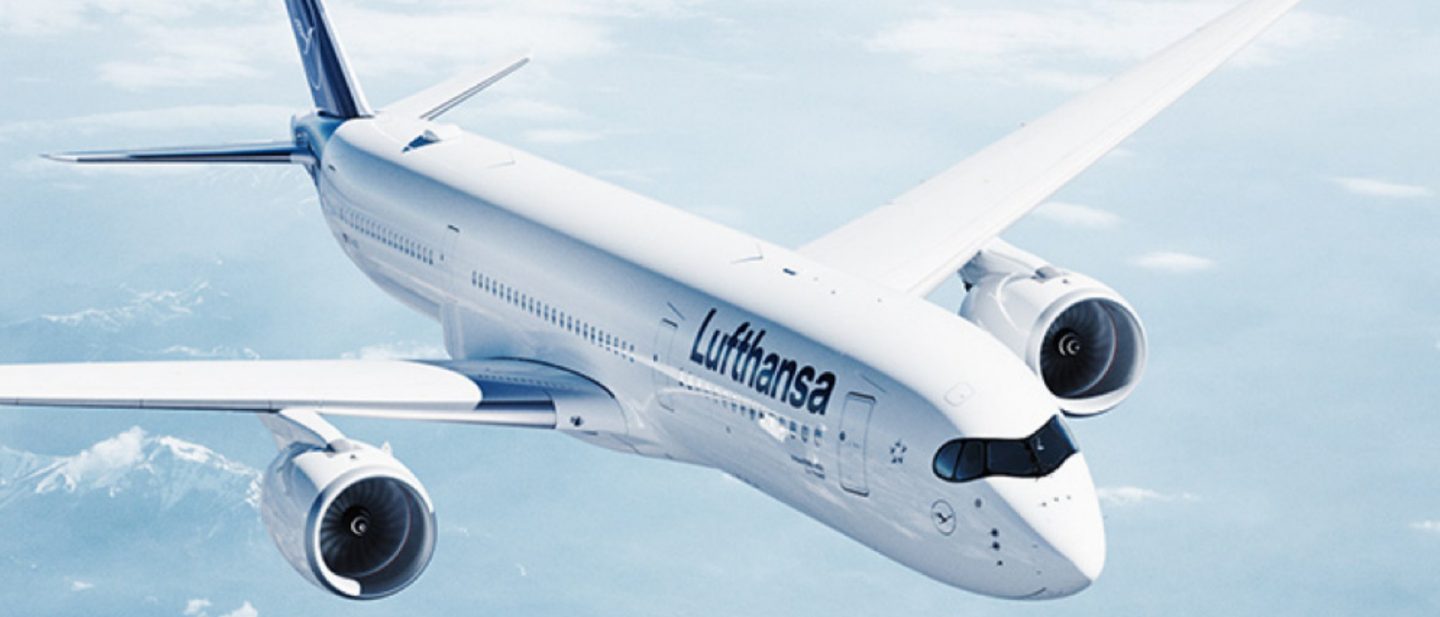 Lufthansa A350 in flight, above clouds and mountains, against a blue sky.