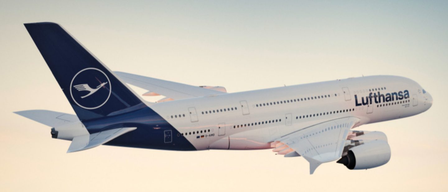 Lufthansa Airbus A380 in flight, white with blue tail against a light sky.