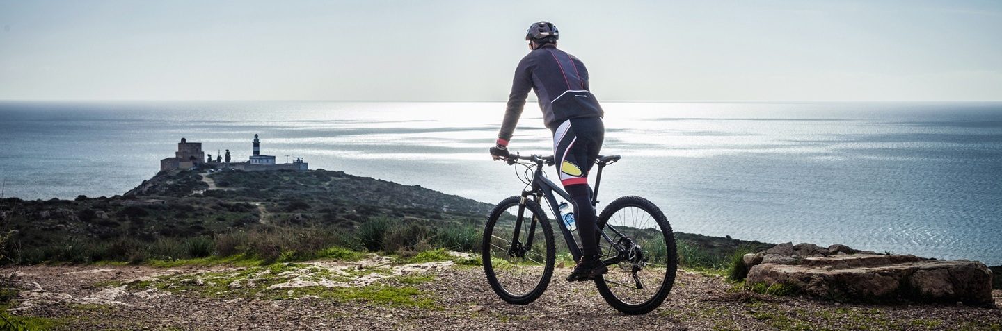 Silhouetted view of male mountain biker on coastal pat