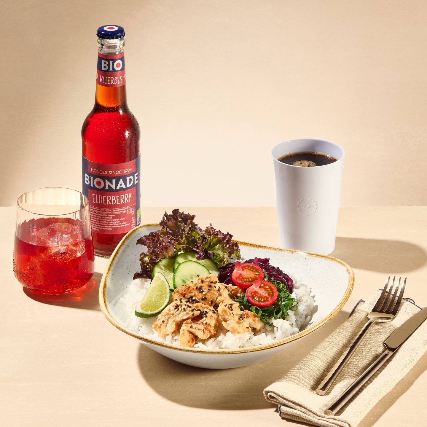 Bowl de arroz com frango, salada e legumes, servida com refrigerante, café e talheres.