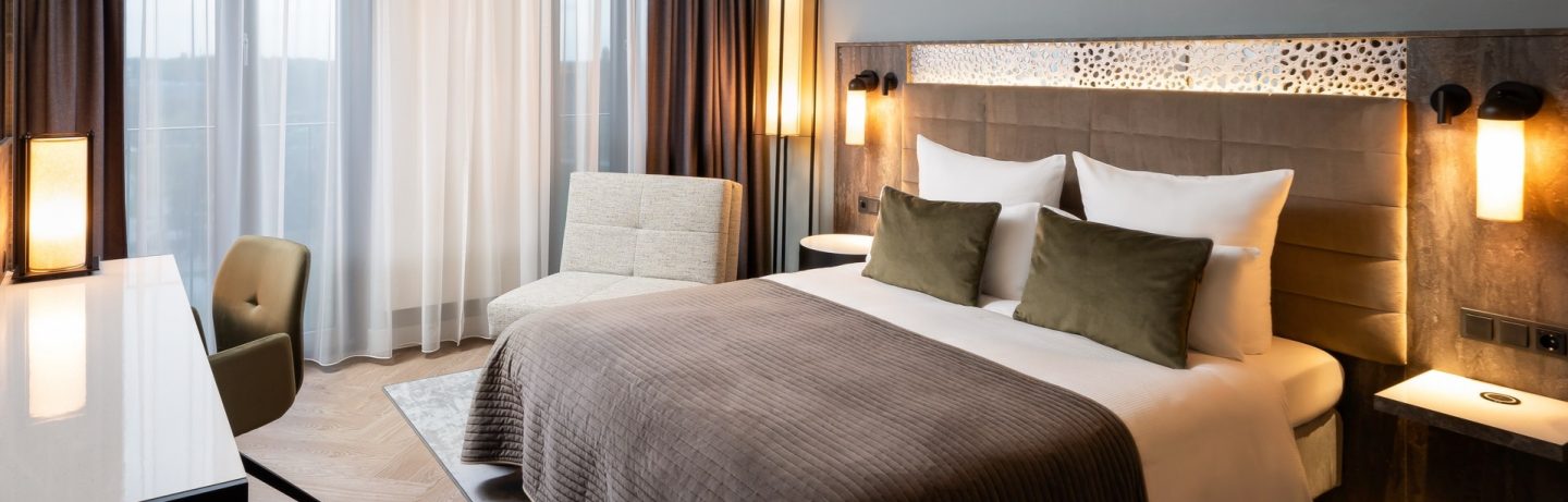 Leonardo Hotels modern room with bed, armchair, desk, and window.