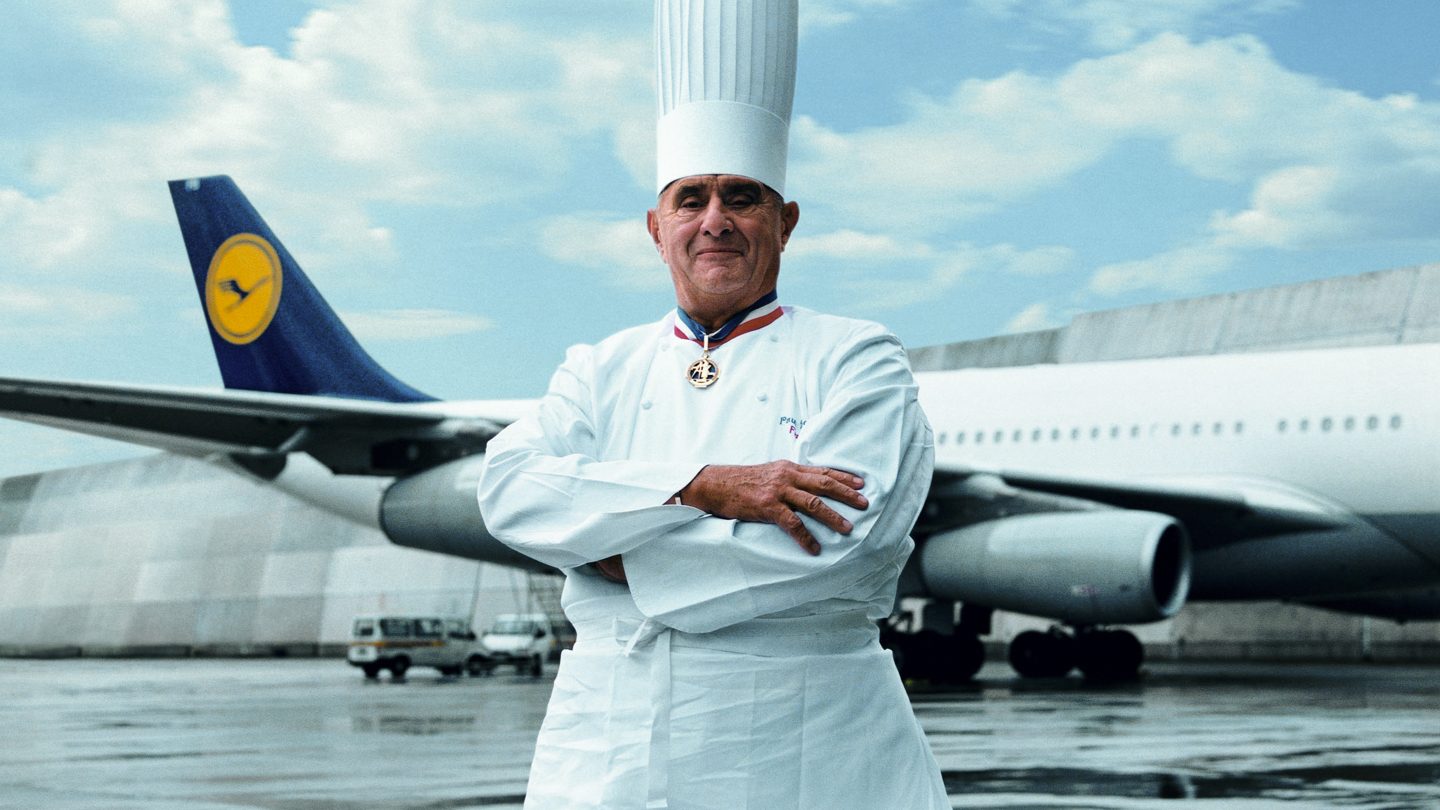 A chef standing in front of a Lufthansa airplane.