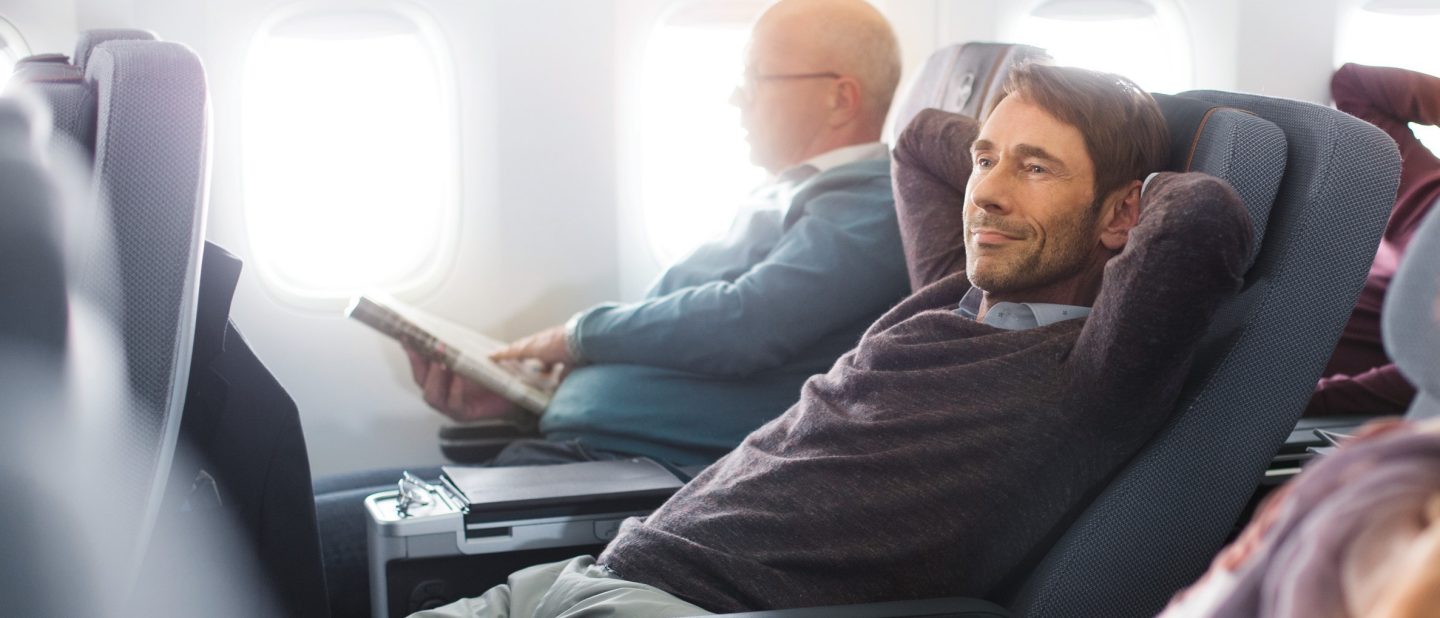 Mann entspannt in der Premium Economy Class // Man relaxing in Premium Economy Class
