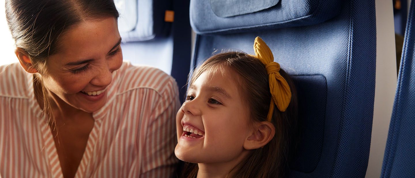Mother sits laughing with her daughter on the plane.