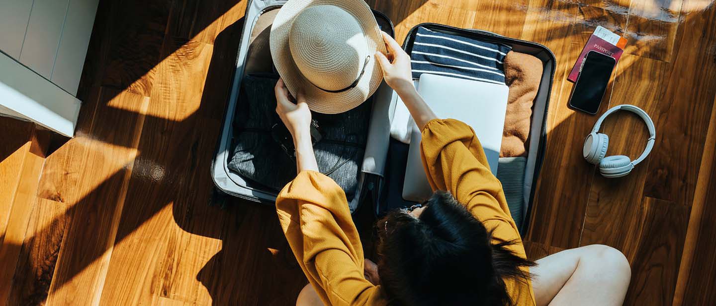 Woman sits on the floor and packs her suitcase.