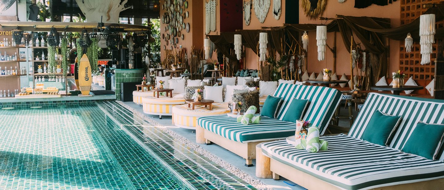 Tropical poolside bar with comfortable striped loungers, exotic decorations, and a refreshing swimming pool.