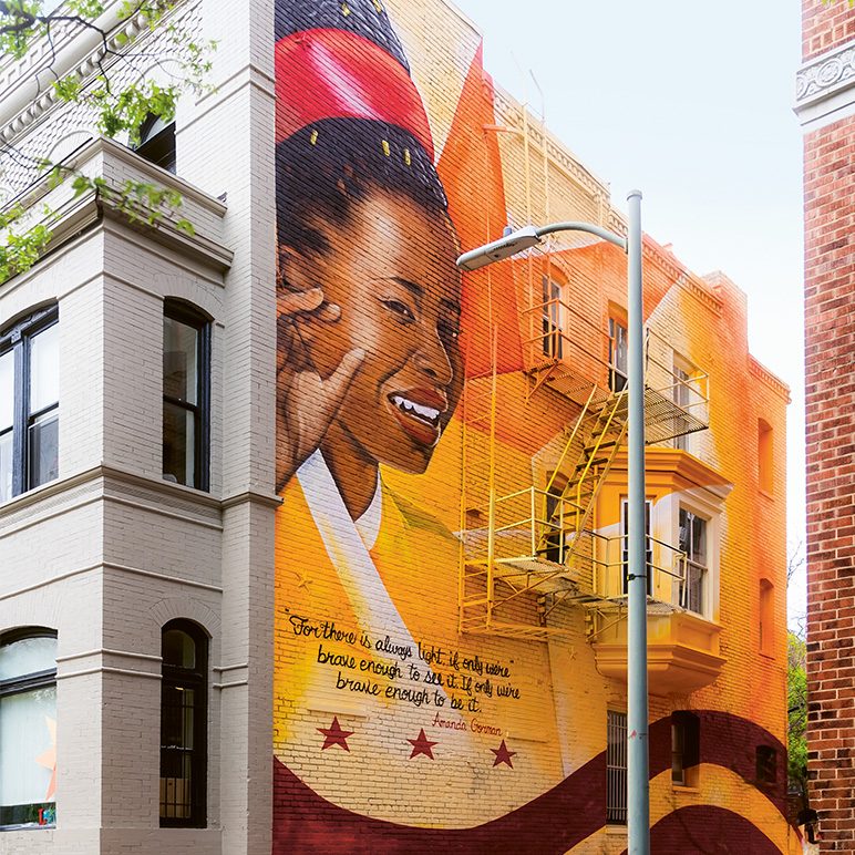 Photo of a colorful mural on a building in Washington, D.C., featuring a smiling woman with inspirational text.
