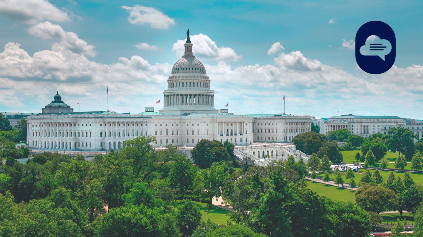 A photo of the United States Capitol Building in Washington, D.C., surrounded by lush greenery under a clear sky.