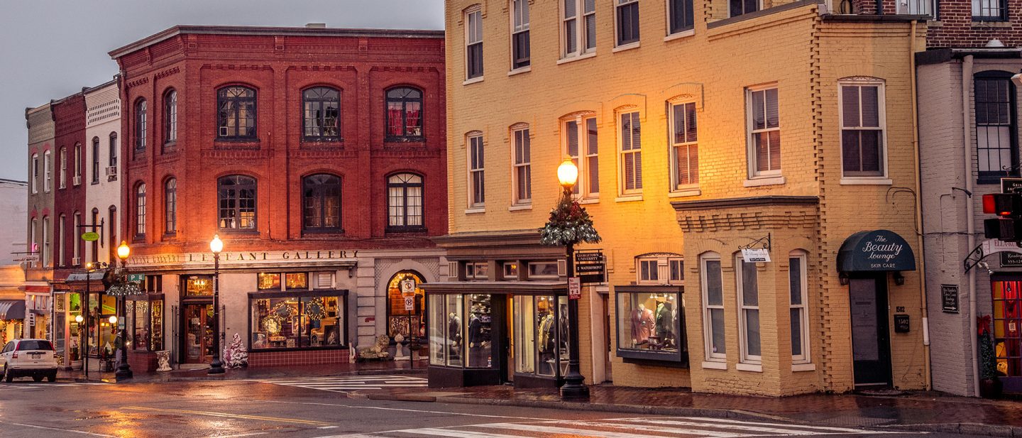 Photo of a historic street in Washington, D.C., lined with colorful brick buildings and shops at dusk.