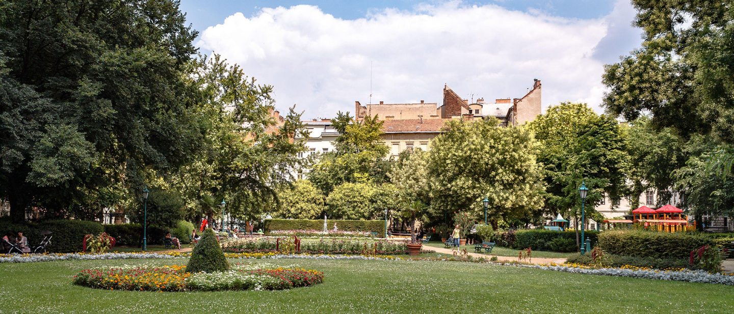  Der Károlyi-Garten mit Blumenbeet und historischen Häusern im Hintergrund