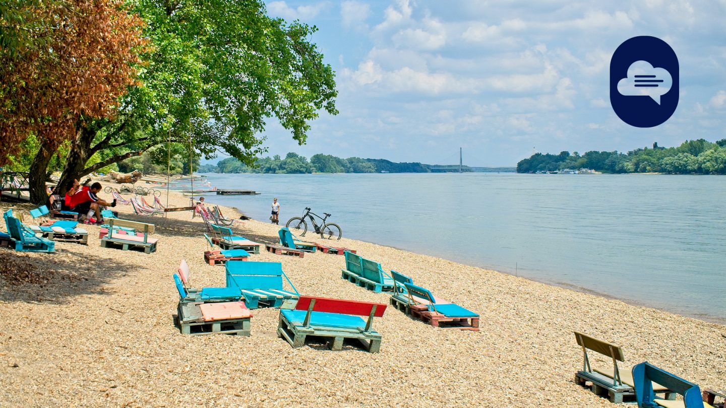 Strand am Fluss mit bunten Palettenliegen und schattigen Bäumen