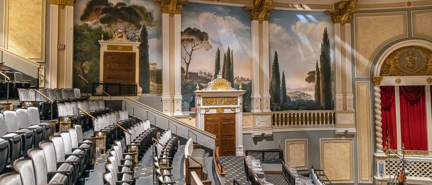 Carolina Theatre hall with landscape murals and red stage curtains