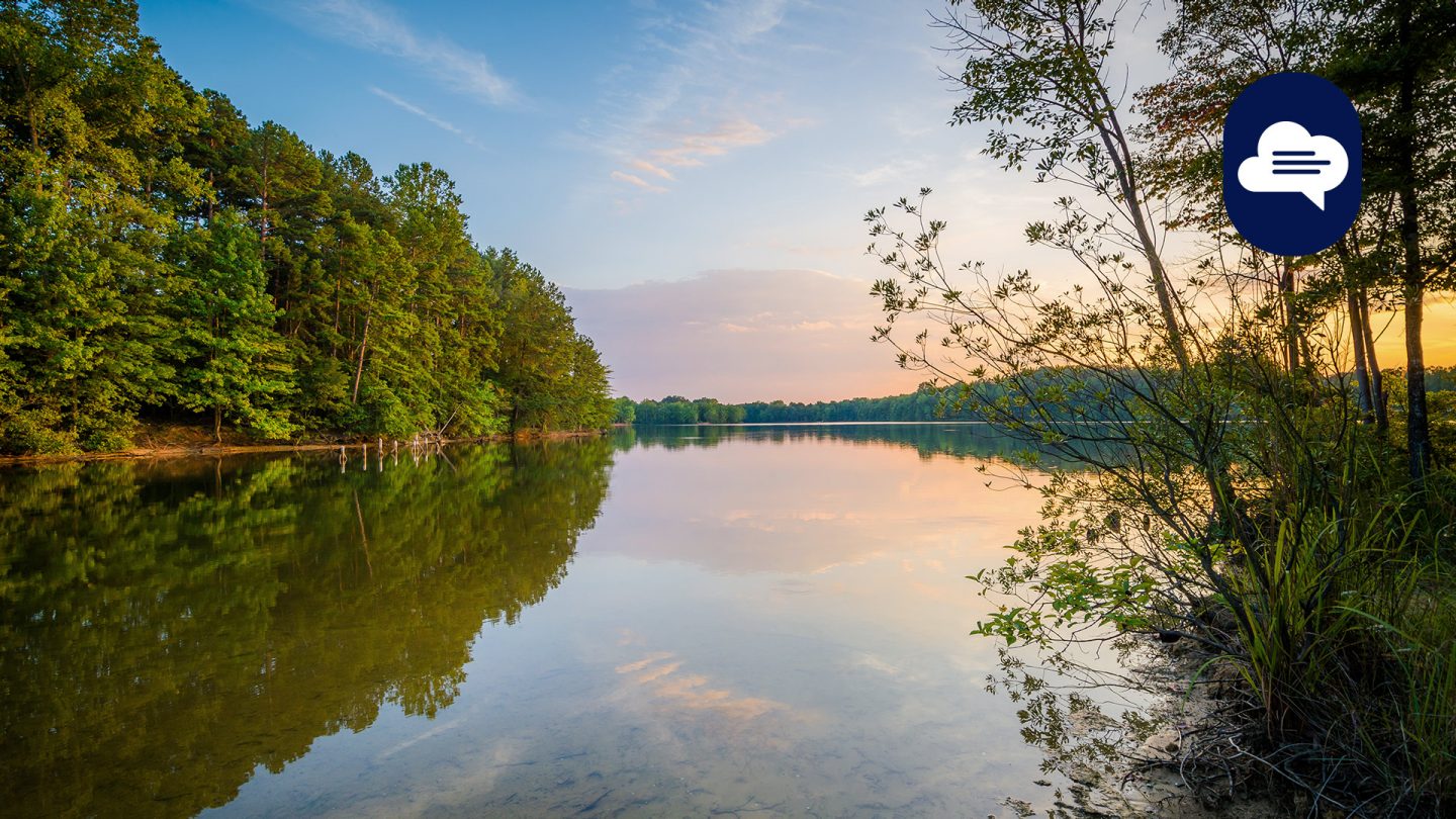 Lake Norman at sunset with calm water and forest shoreline