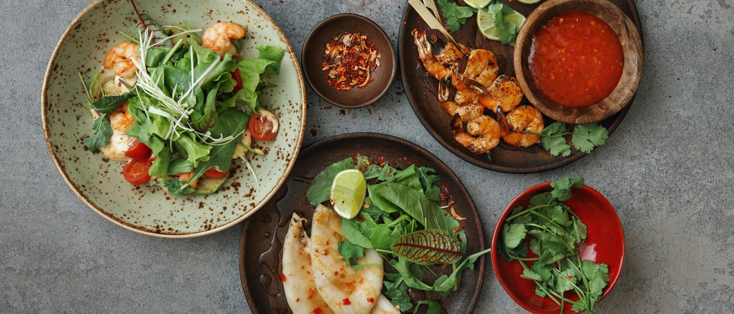 Verschiedene asiatische Gerichte mit Garnelen, Salat und Dips