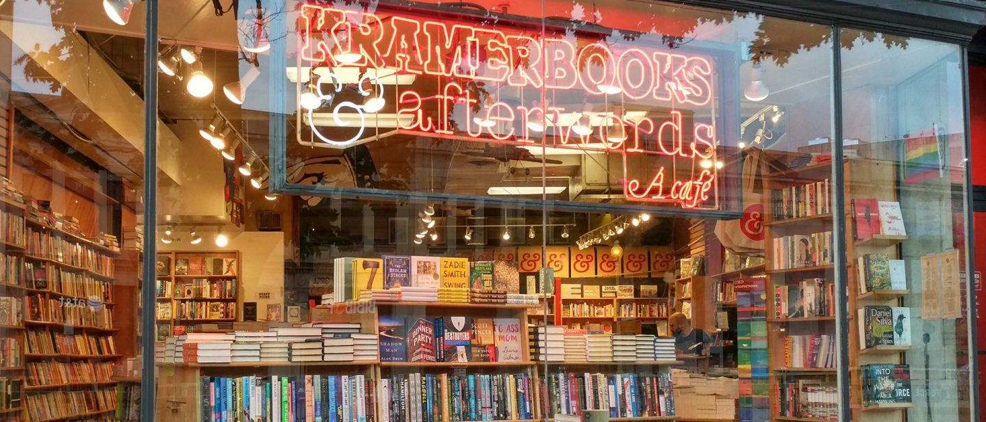 Foto einer Schaufensterauslage eines Buchladens mit einem Leuchtschild, auf dem „Kramerbooks & Afterwards Café“ steht