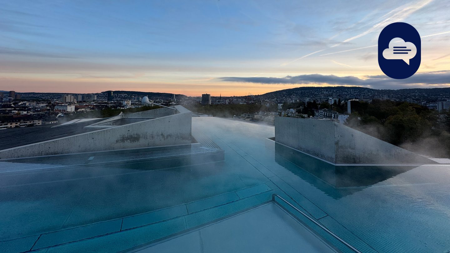 Sunset view over Zurich's cityscape with mist from the infinity pool on the Hürlimannbad & Spa rooftop terrace.
