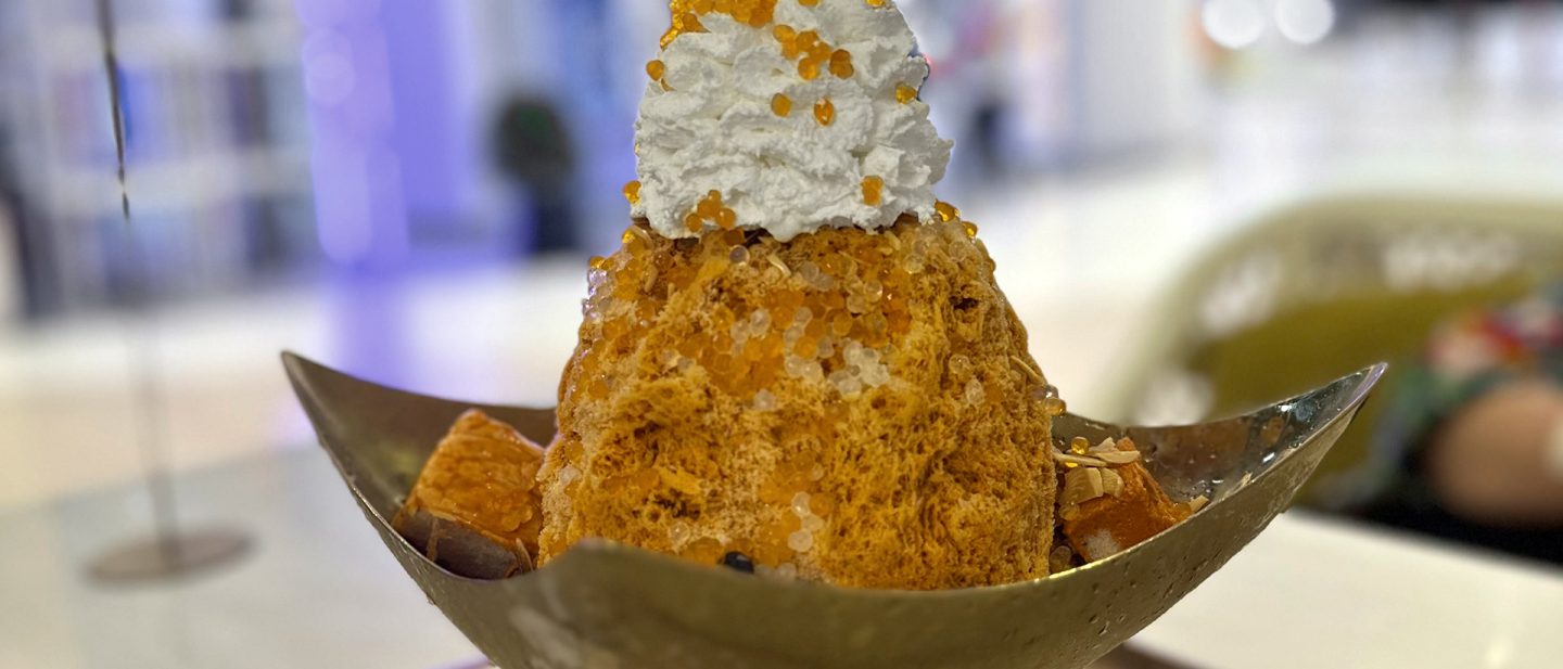 Thai shaved ice dessert topped with whipped cream and pearls in a golden bowl
