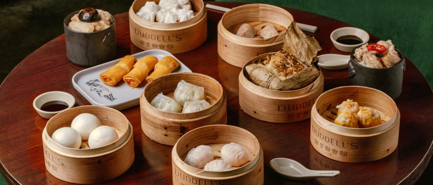 An assortment of dim sum in bamboo steamers on a dark wooden table at Duddell's