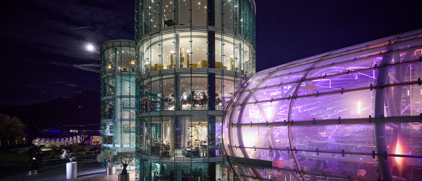 Illuminated glass towers and the curved facade of Hangar-7 in Salzburg at night