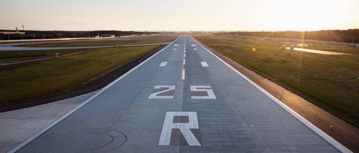 View of a long airport runway during sunset or sunrise
