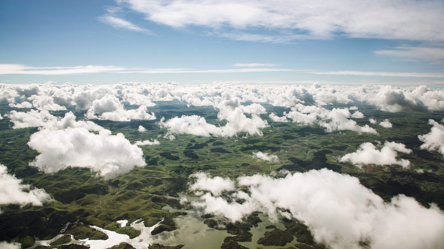 Aerial view of a green hilly landscape with lakes under a thick layer of clouds