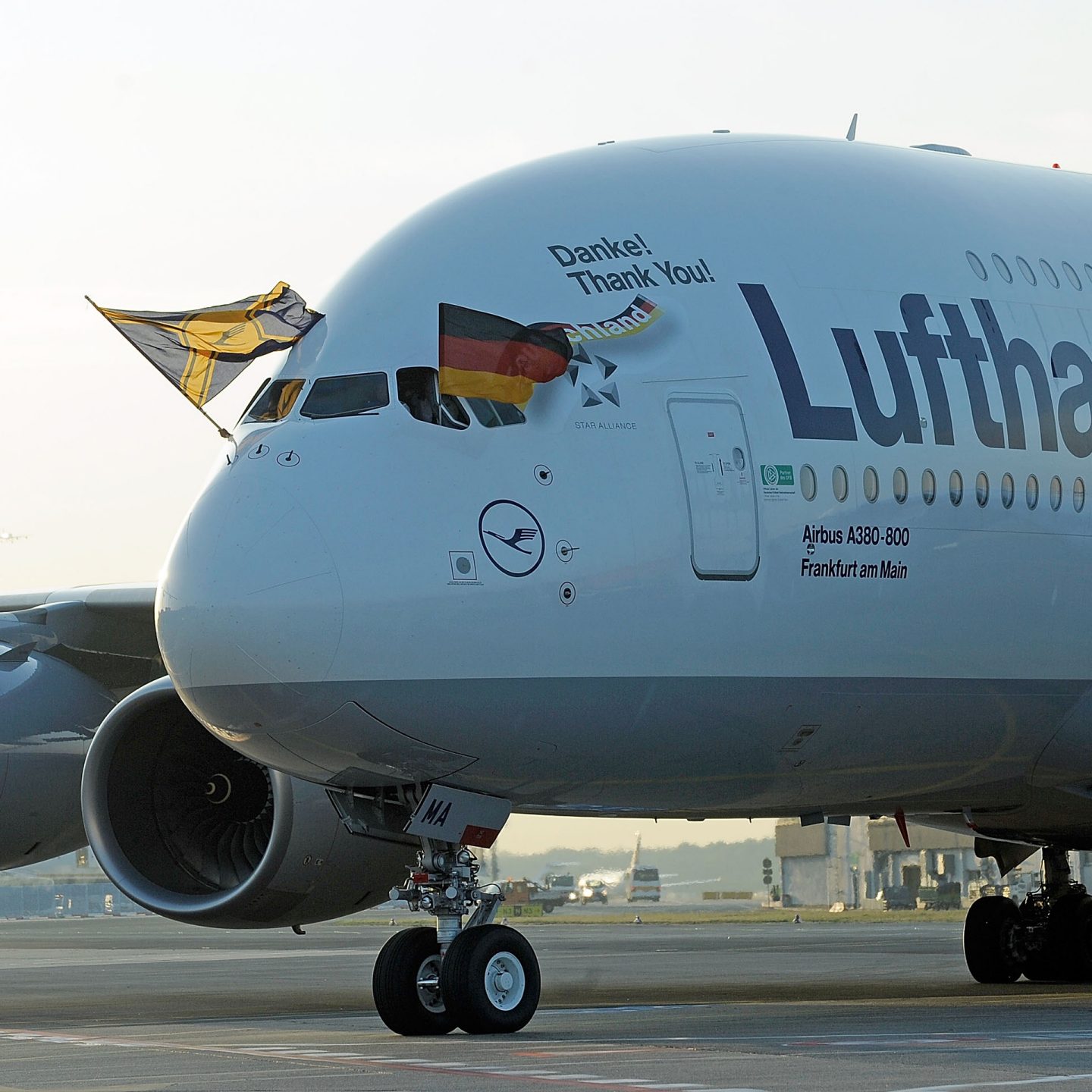 Close-up of a Lufthansa Airbus A380 decorated with the German flag and another flag.