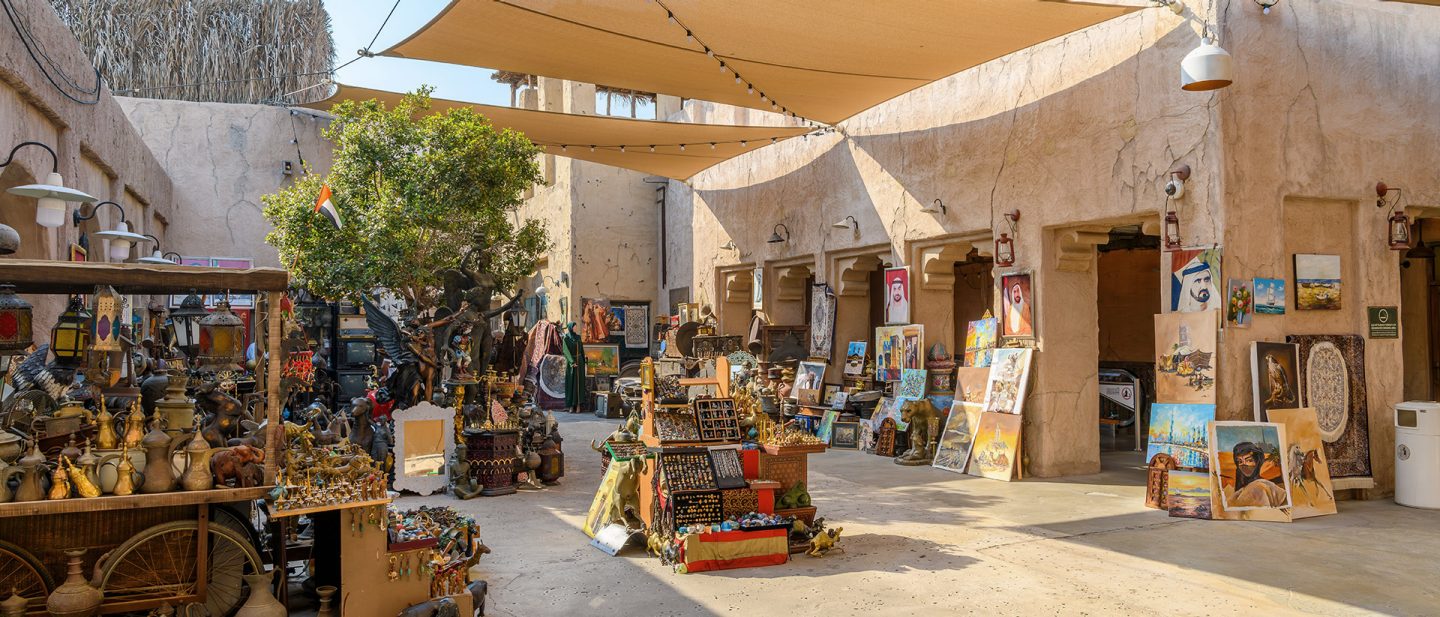 Traditional Arab market in Dubai featuring paintings and antiques in a sunny courtyard