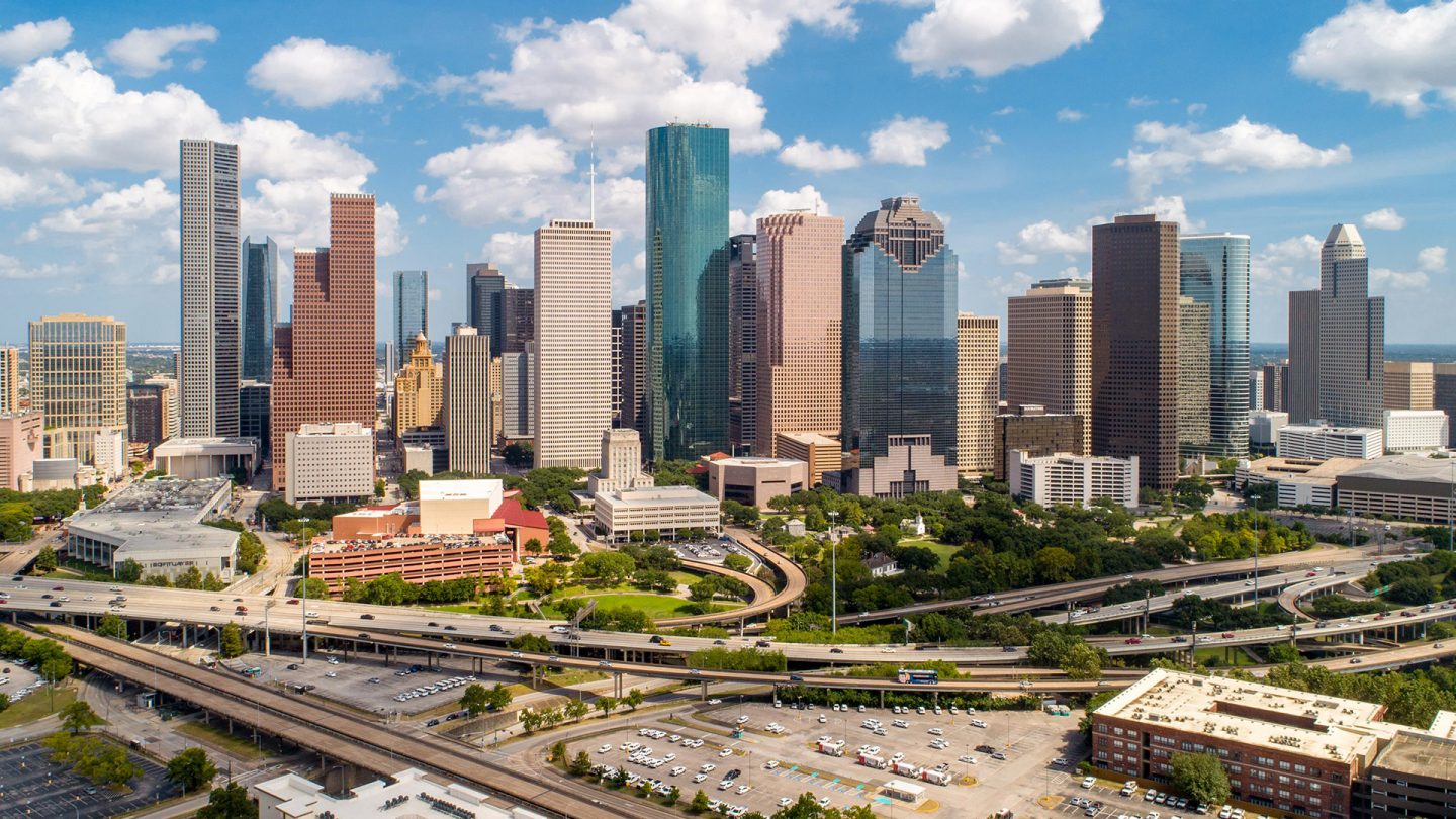 Modern skyscrapers rise into a cloudy sky above the Houston city skyline