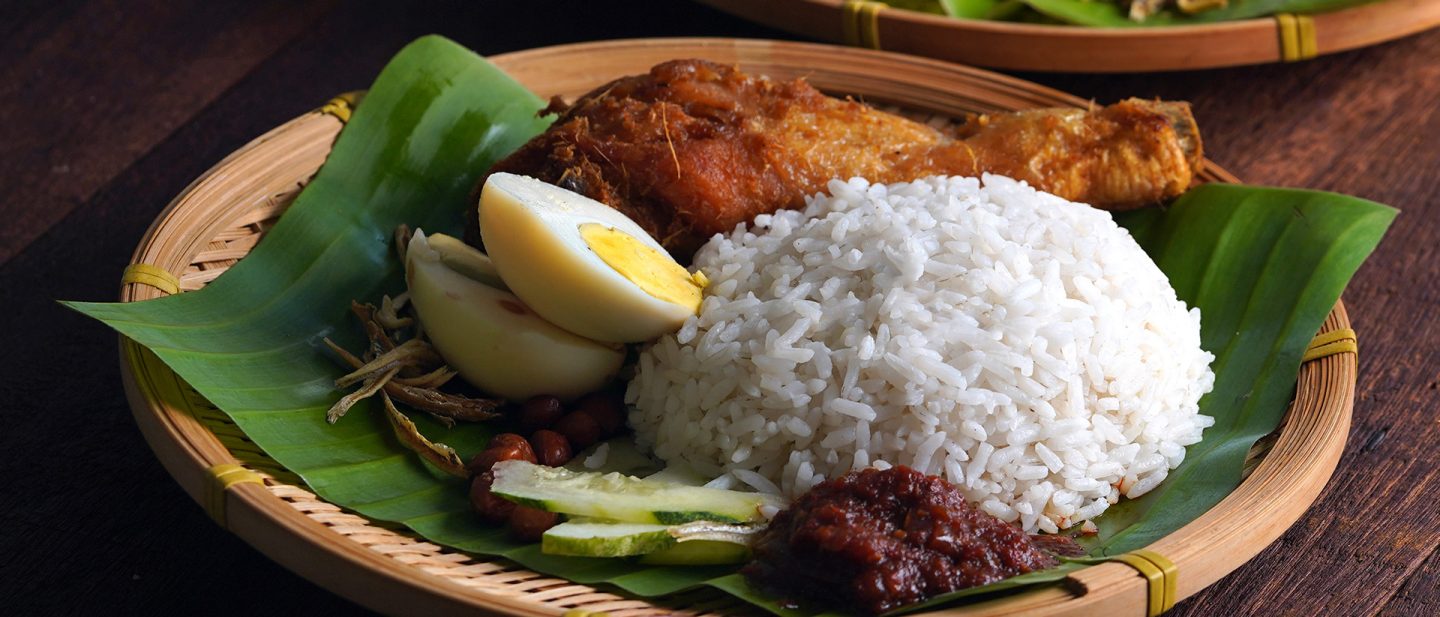 Nasi lemak with rice, fried chicken, egg, and sambal served on a banana leaf