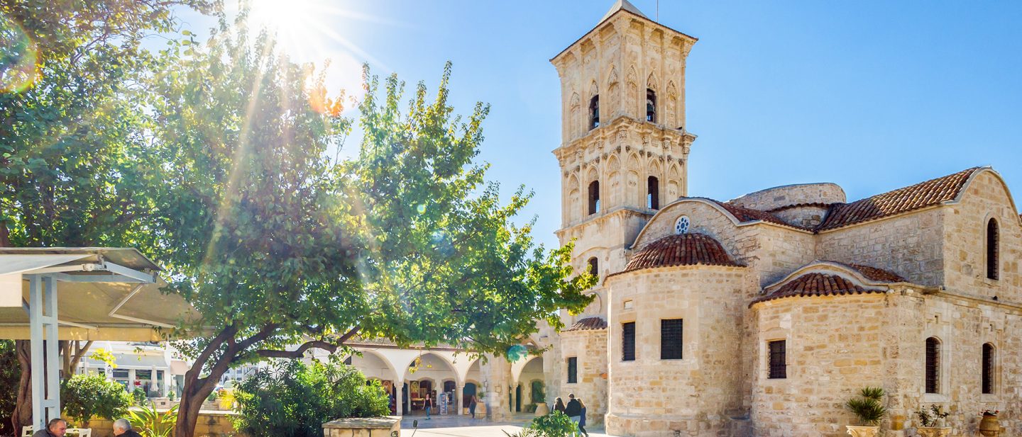View of a historic stone church with a prominent bell tower in bright sunlight