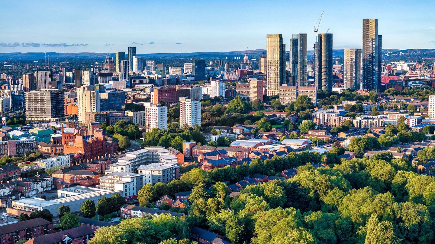 Modern Manchester skyline featuring prominent skyscrapers and green parkland in the foreground