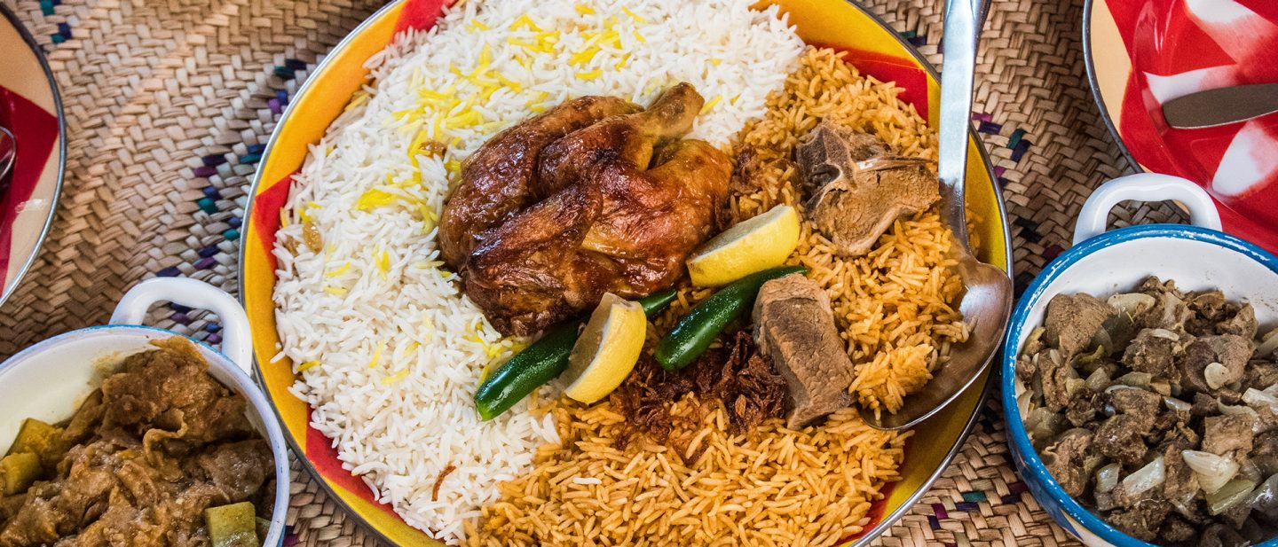 Platter of Kabsa: roasted chicken and other meat on two types of rice with lemon and green chilies