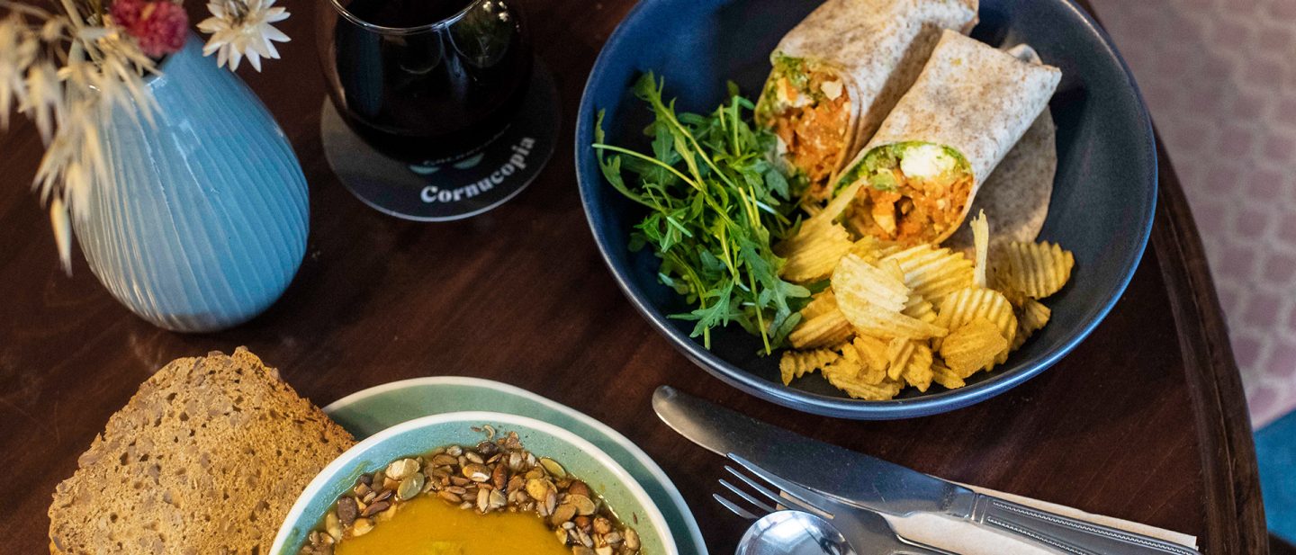 Healthy lunch with soup, wrap, chips, and salad on a wooden table