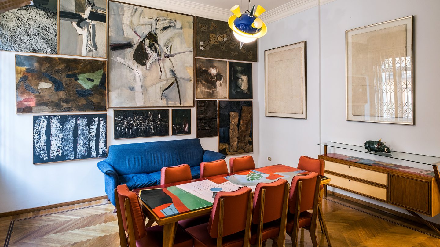 Art-filled modern living room in Milan with colorful furnishings and multiple abstract paintings on the walls